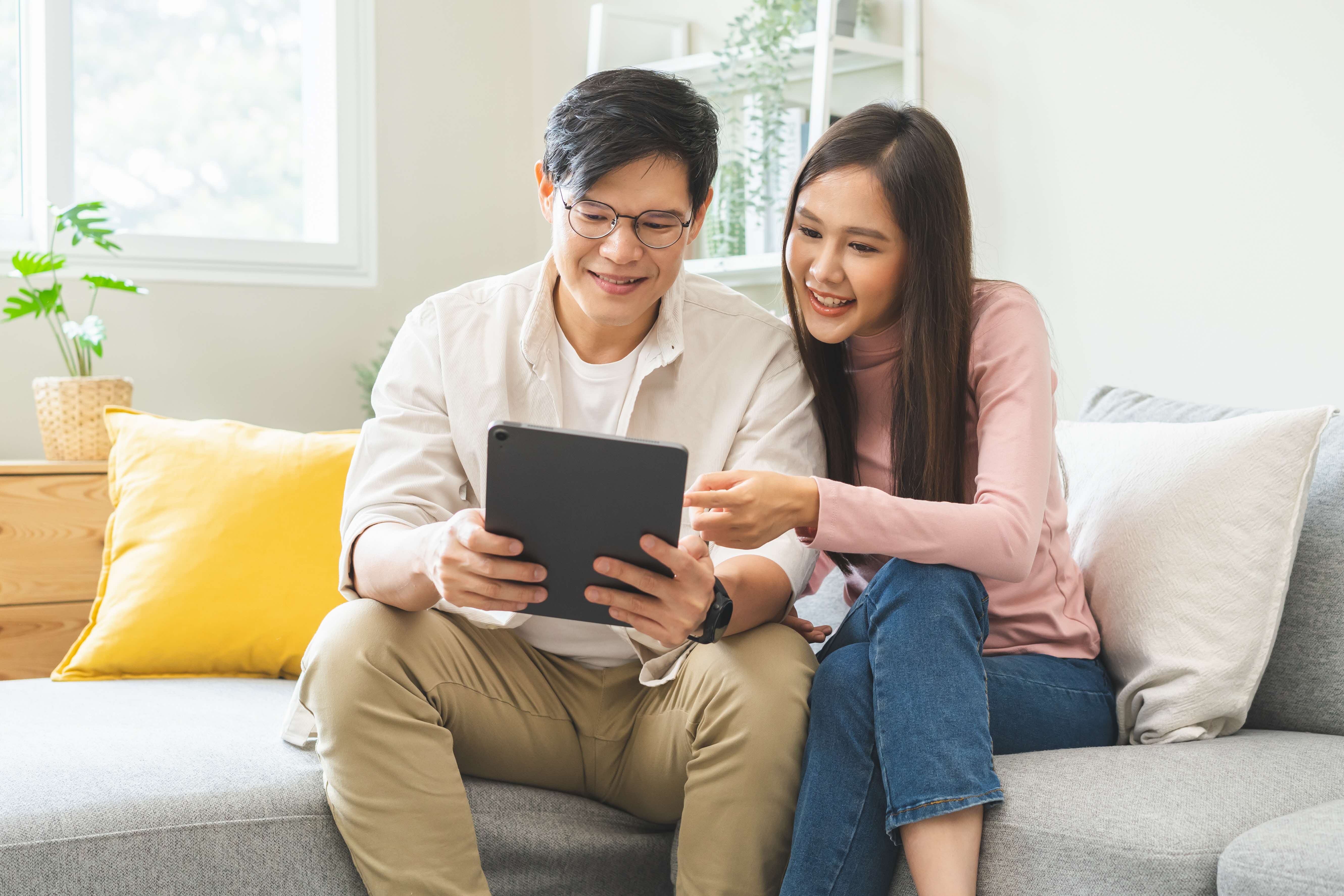 couple in mid 30s looking at a tablet happily