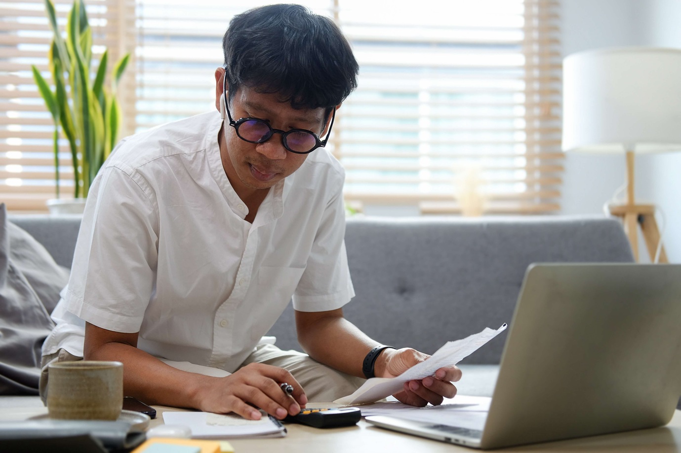 A man wearing glasses using a calculator