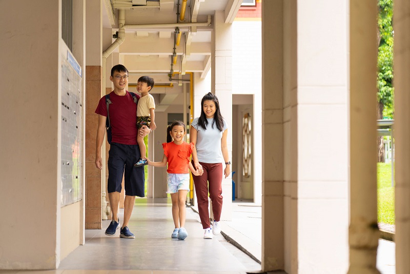 young family walking under void deck