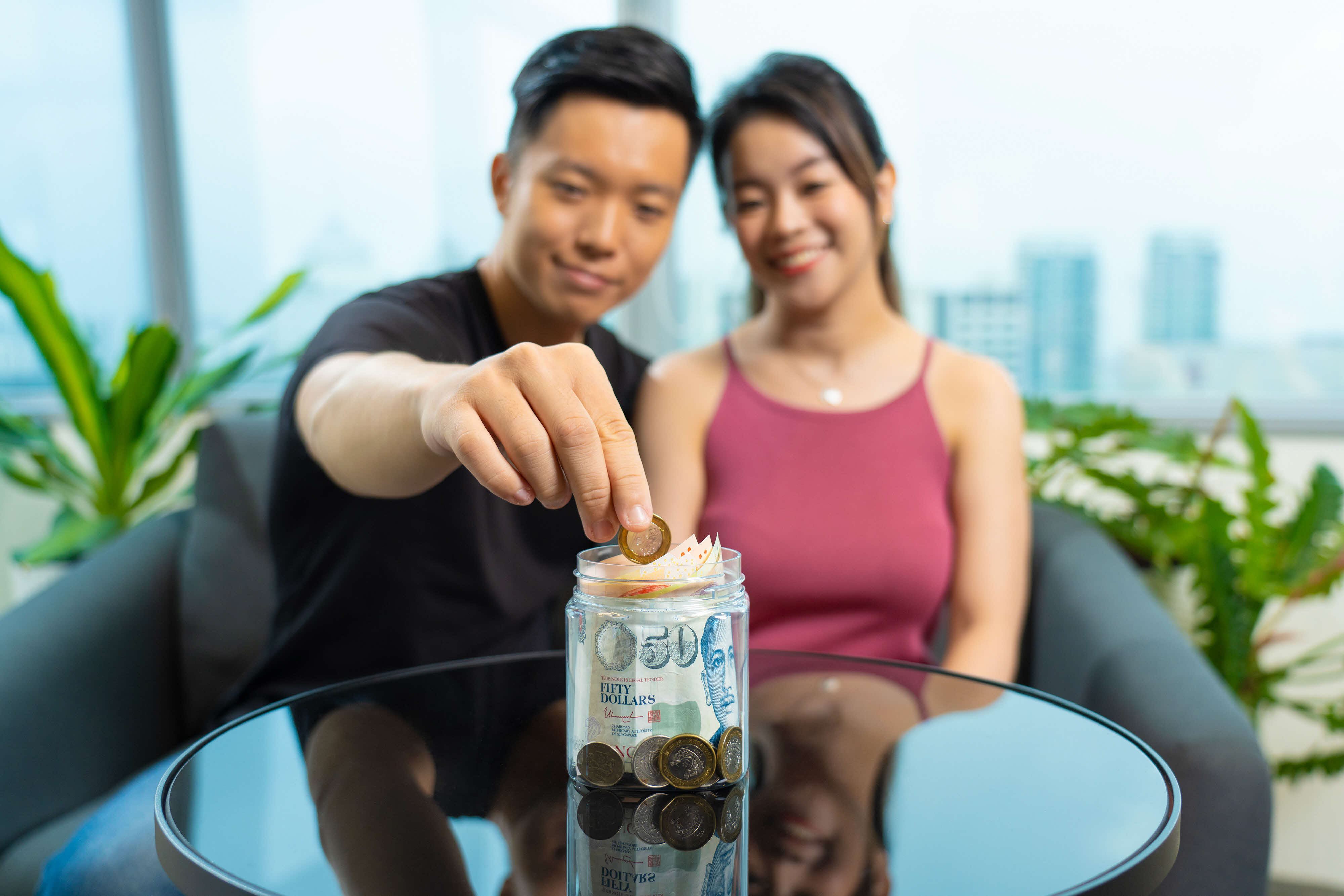 a young couple putting their money in a jar