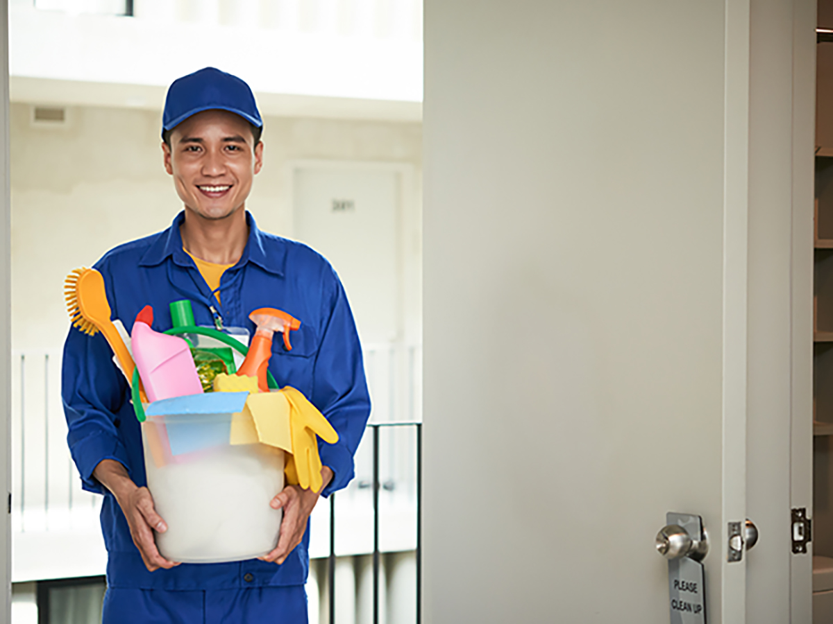 Delivery man in blue outfit smiling and holding box