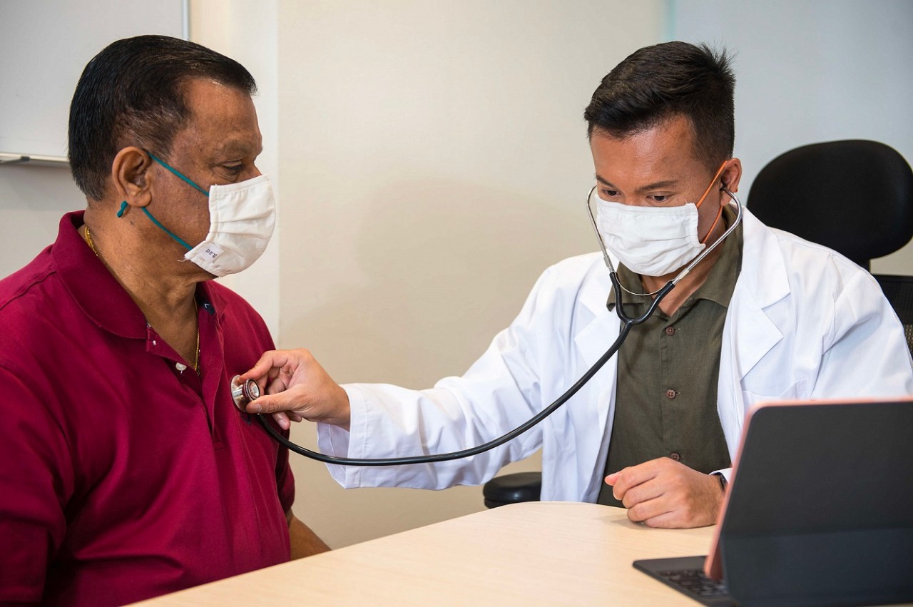 Young Asian doctor talking to elderly patient