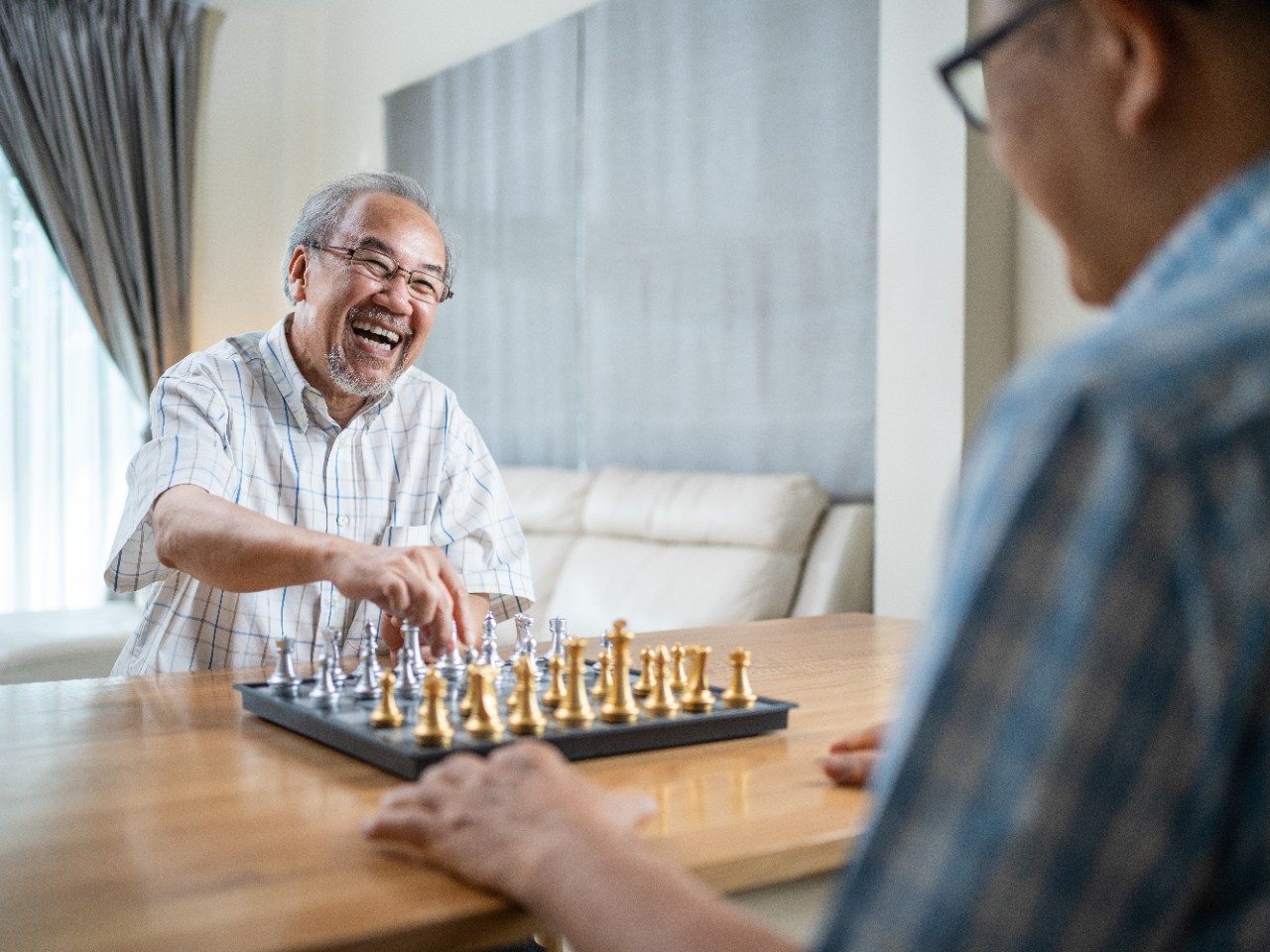 elderly man enjoying playing chess with his friend