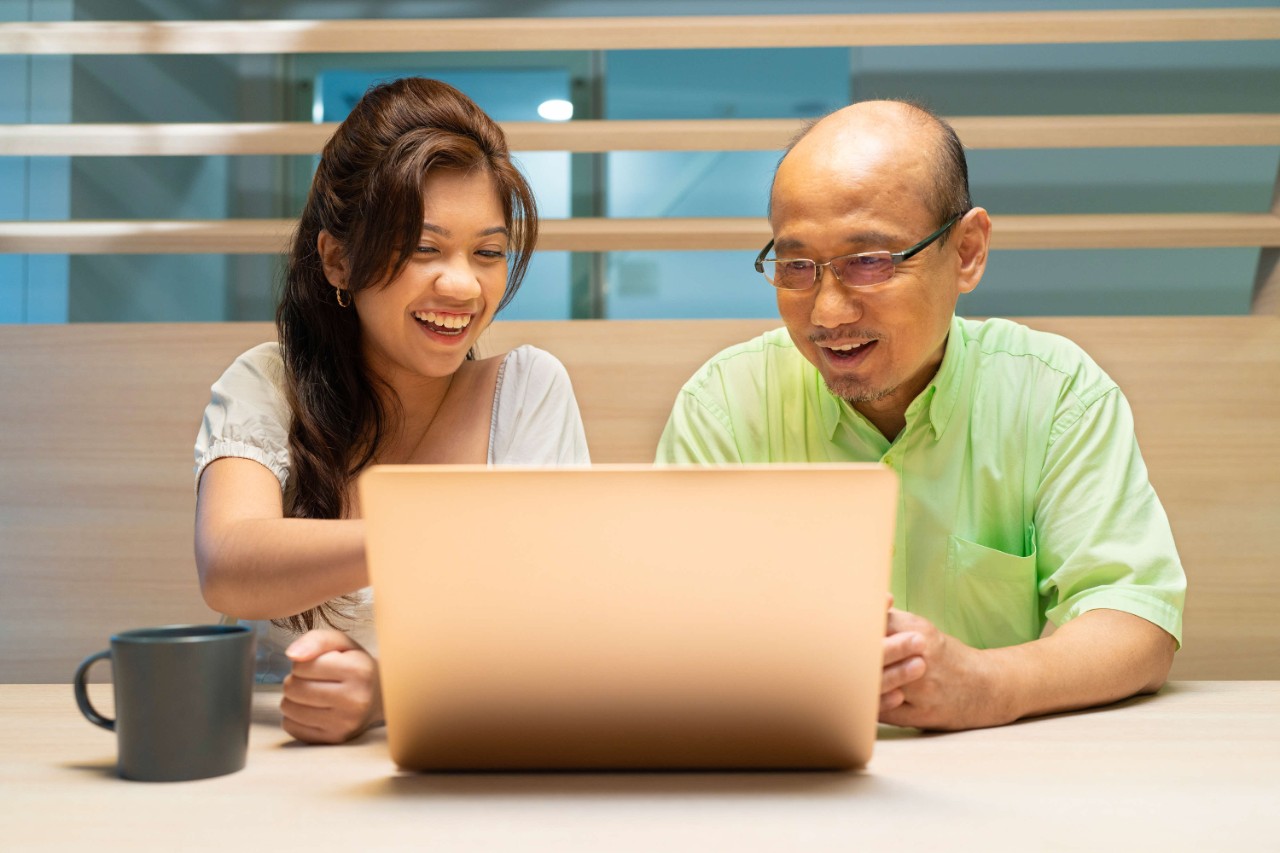 Father and daughter planning for retirement using laptop