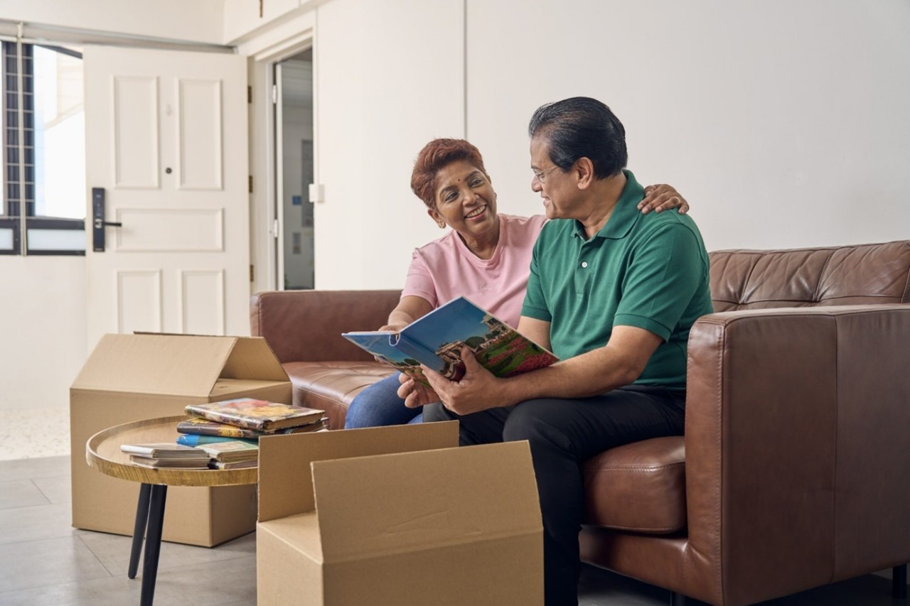 A family of 3 sheltered under a canvas that is held in the shape of a roof.