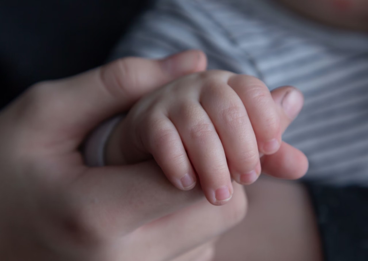 Adult hand holding baby hand