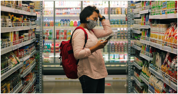 Women holding her phone and looking at the food shelf