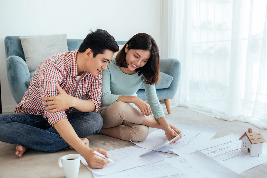 Two young couples looking at the floor plan of their home