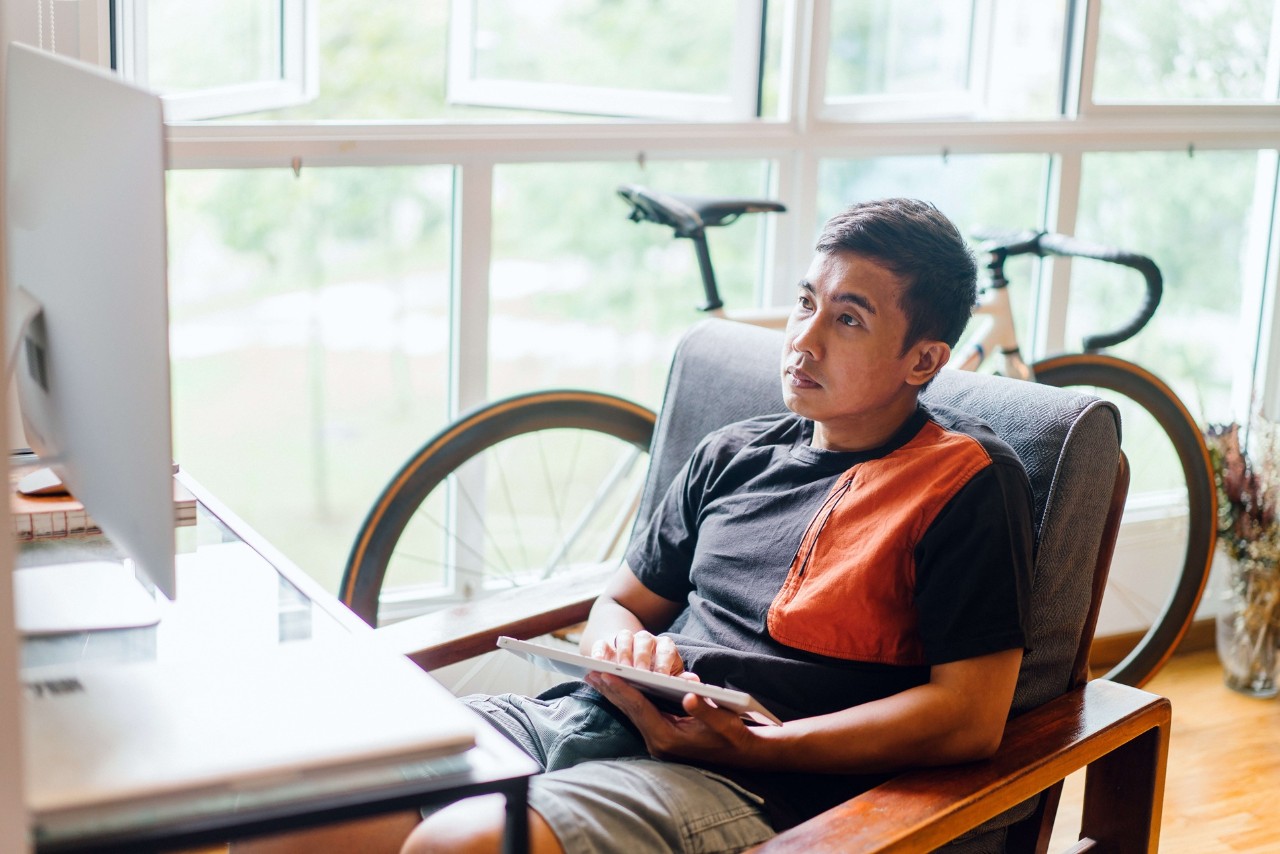 Man relaxing at home and looking at his tablet