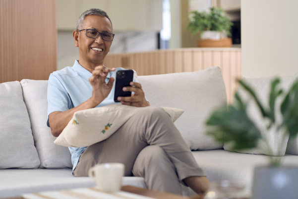 Senior man relaxing at home with his mobile phone