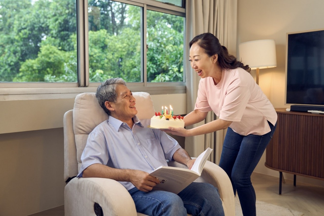 A family of 3 sheltered under a canvas that is held in the shape of a roof. 