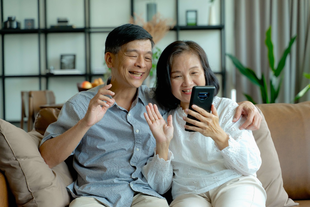 elderly couple happily doing a video call in their home