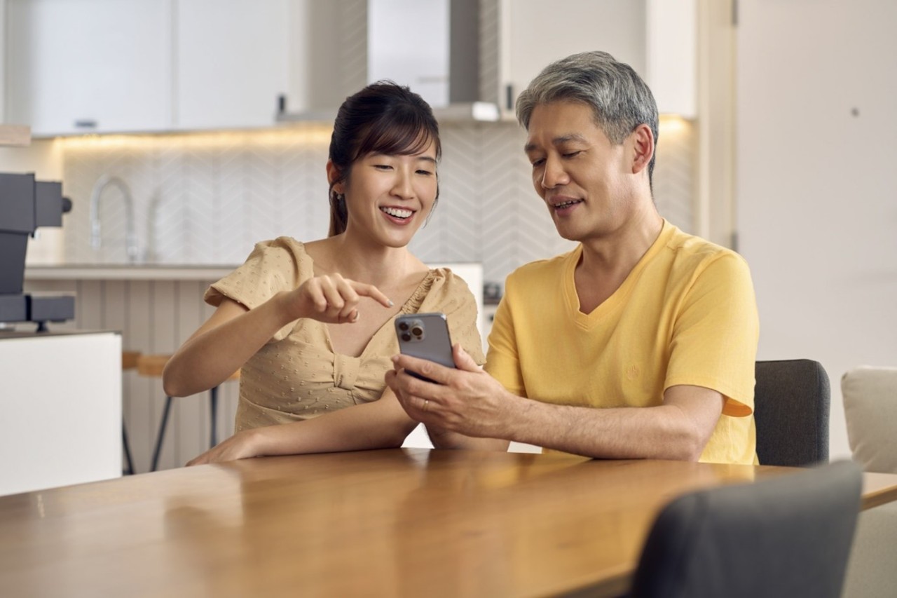 A young female is showing her father how to use a phone