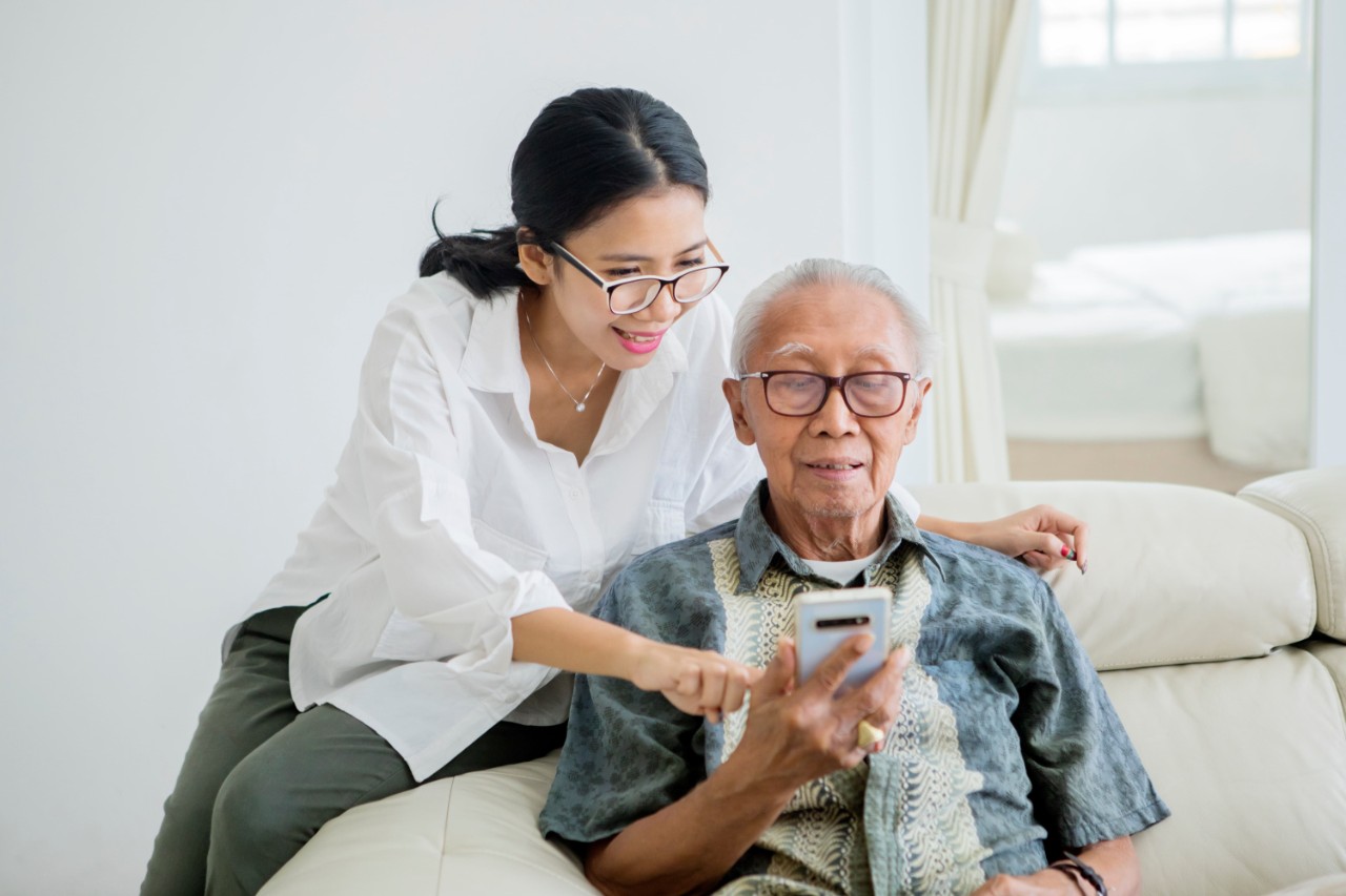 Caregiver smiling with a senior using a phone