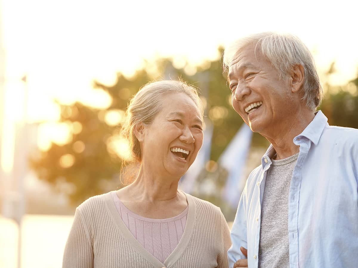 Elderly couple smiling outdoors in the sun