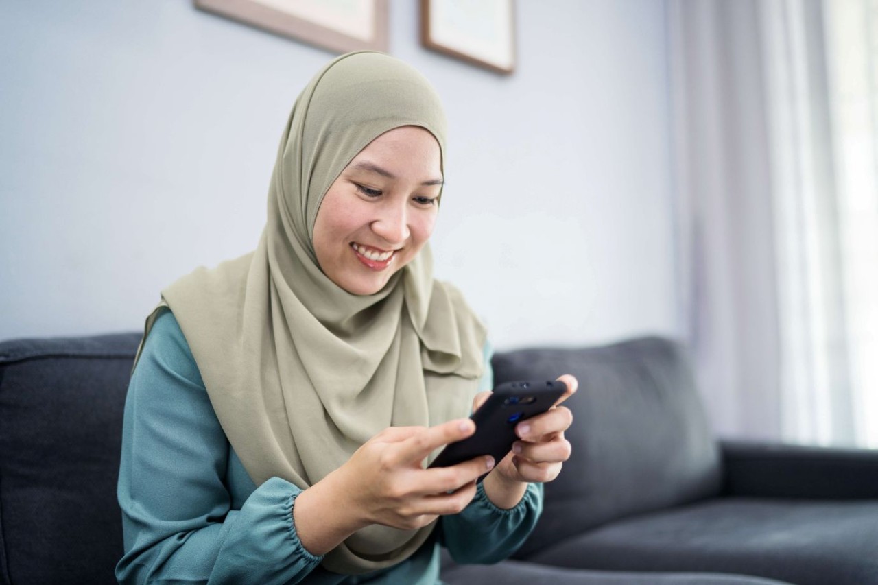 A smiling woman looking at her phone