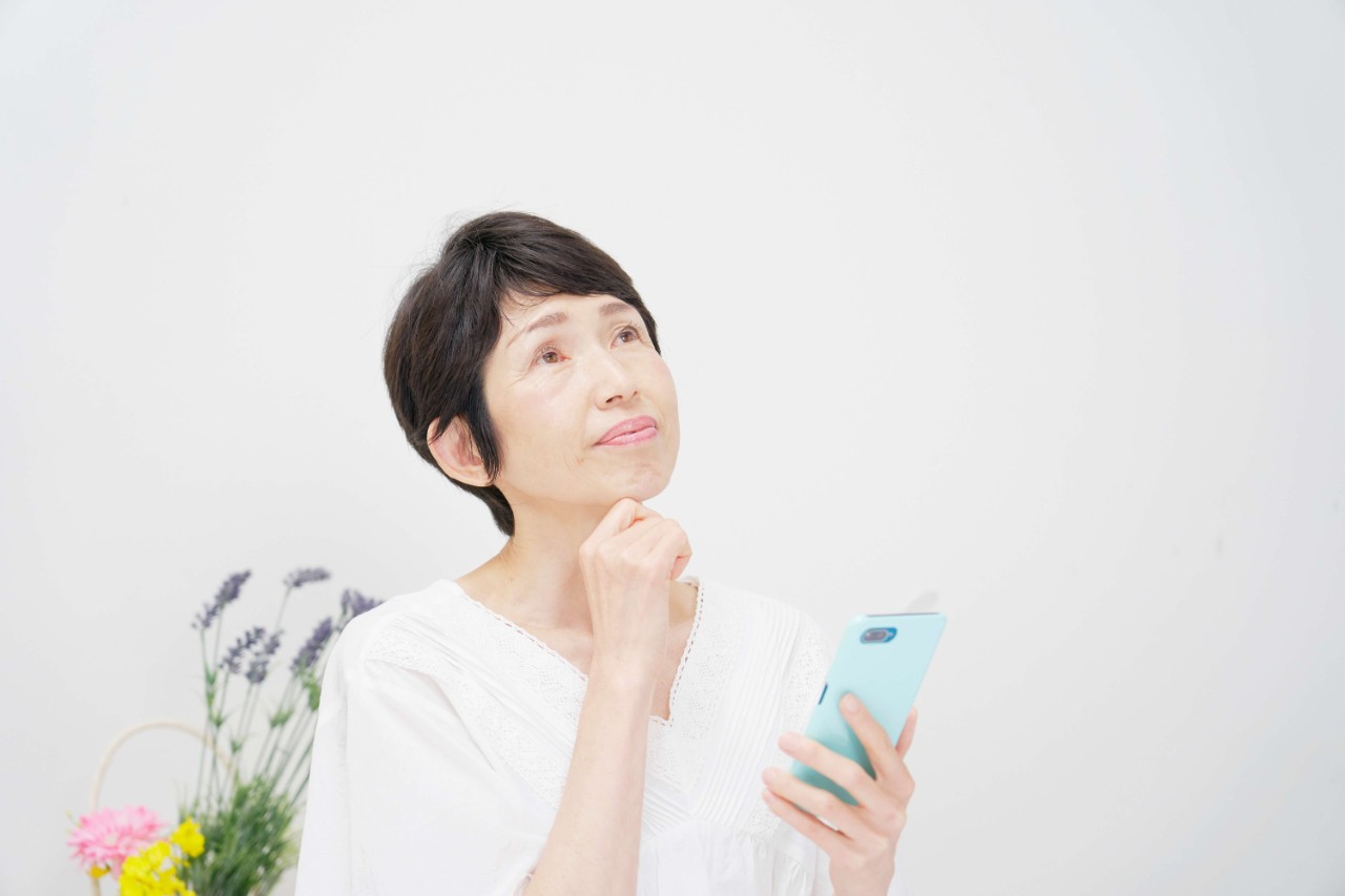Asian lady checking her phone, thinking