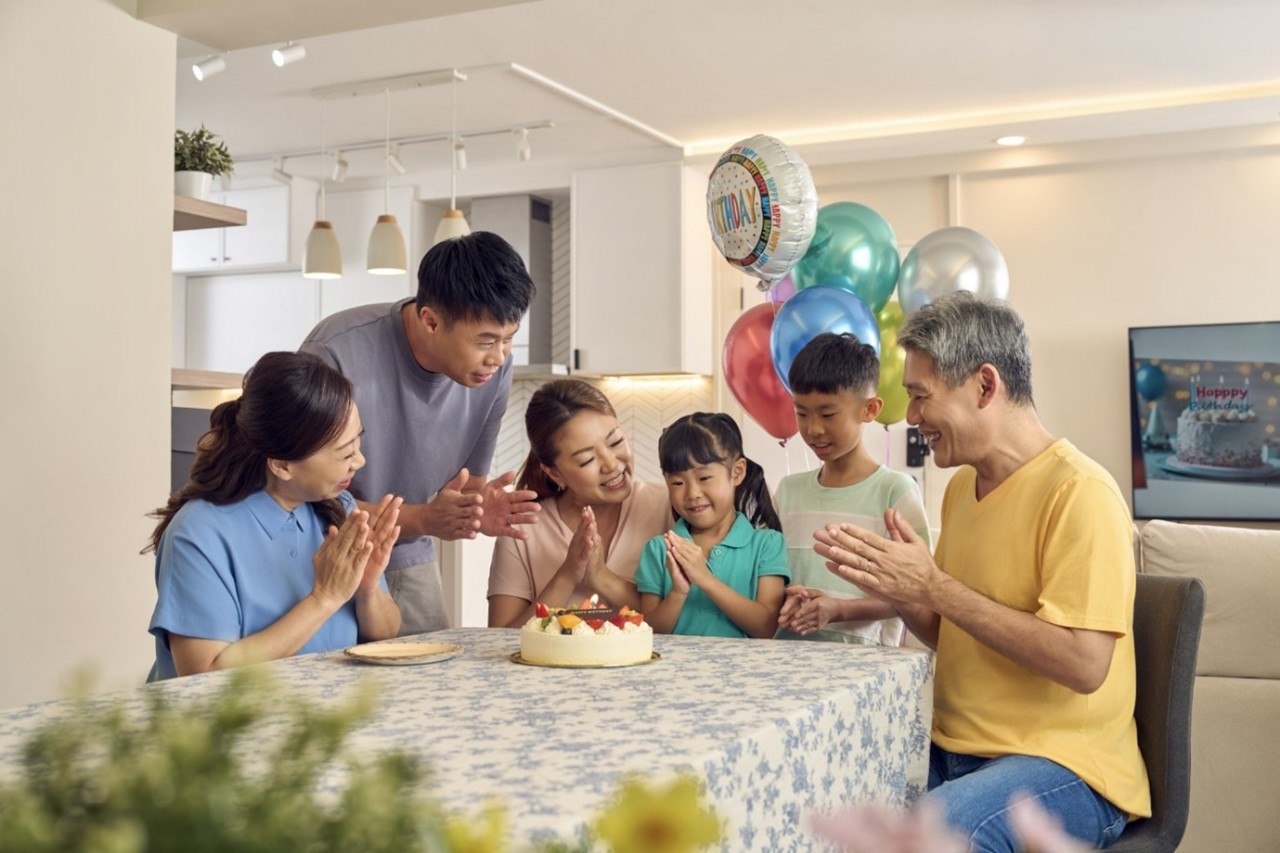 A family of 3 sheltered under a canvas that is held in the shape of a roof. 