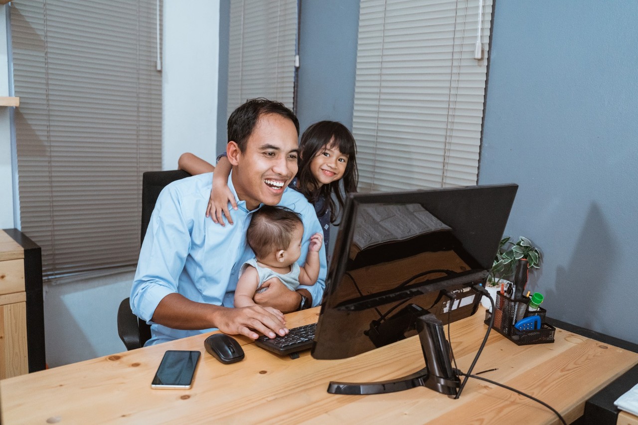 Father with two children at the study table working from home