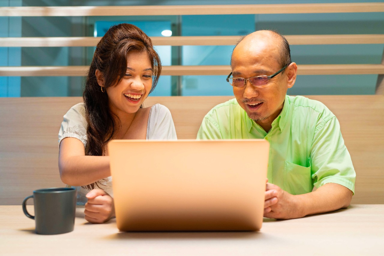 Young lady looking at a laptop with an elderly man