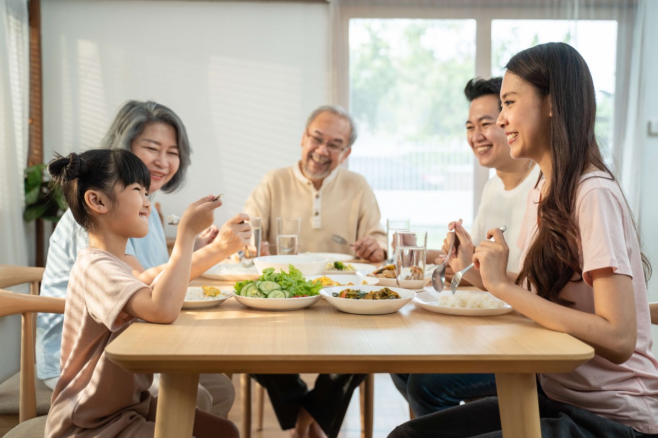 asian family with grandparents and granddaughter having a meal at the dining table