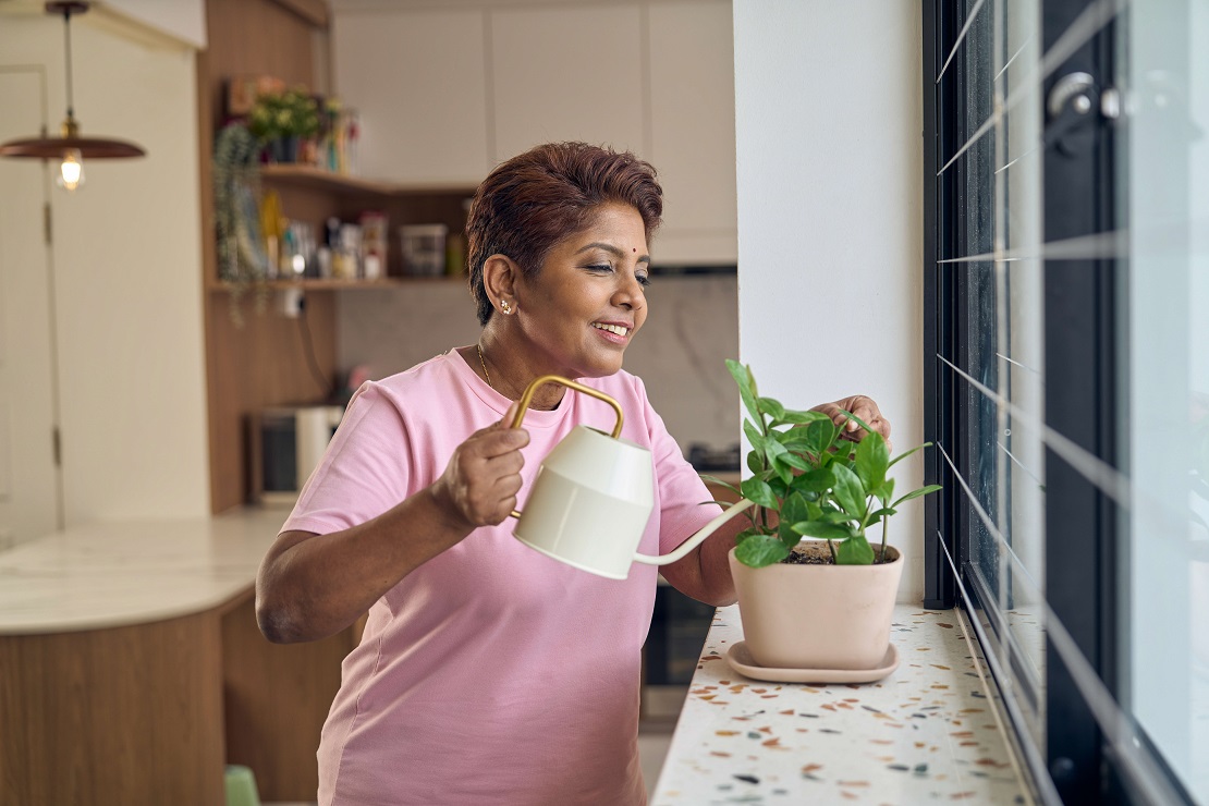 Woman watering plant by window