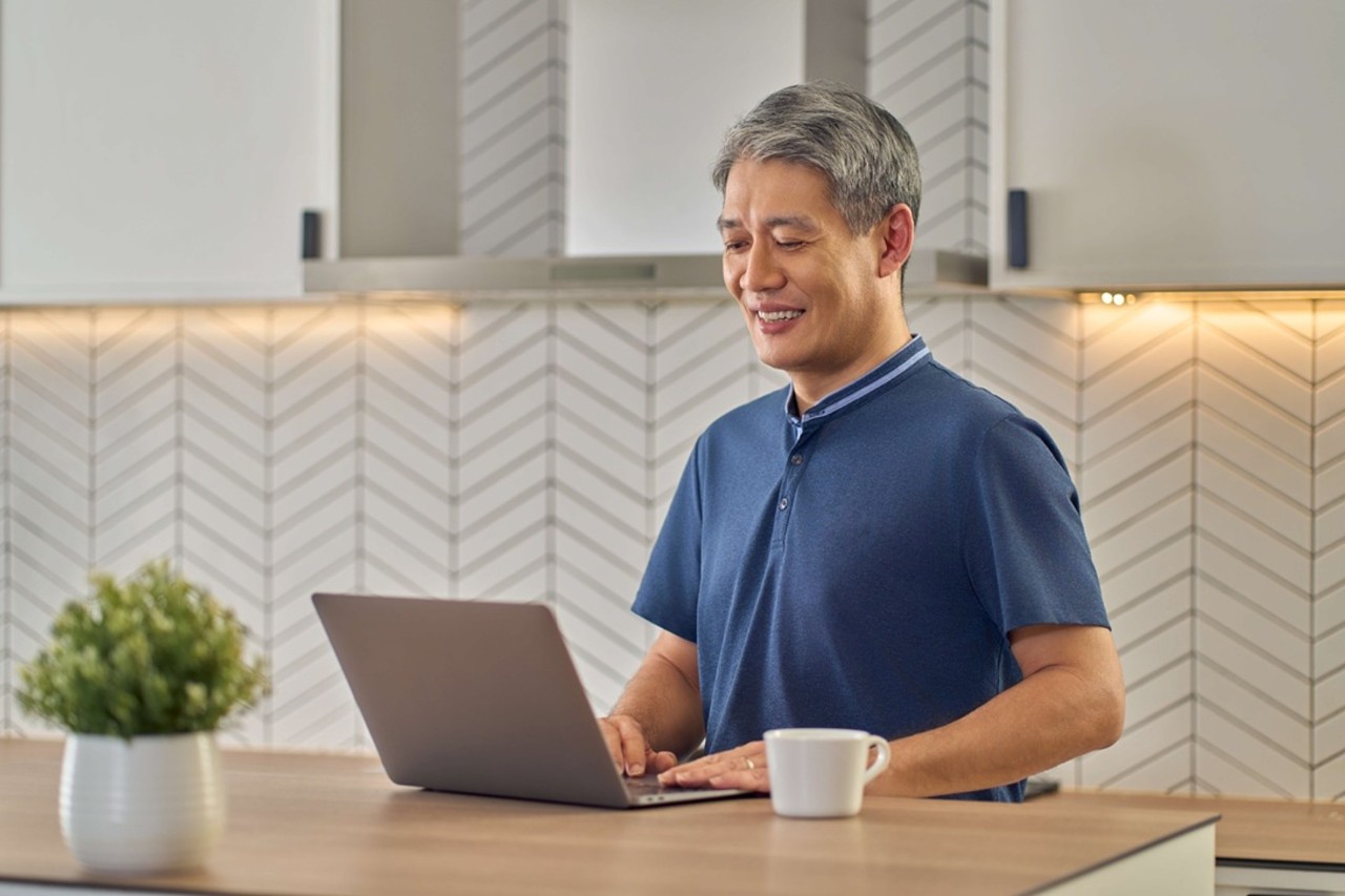 Man looking at his laptop in his kitchen
