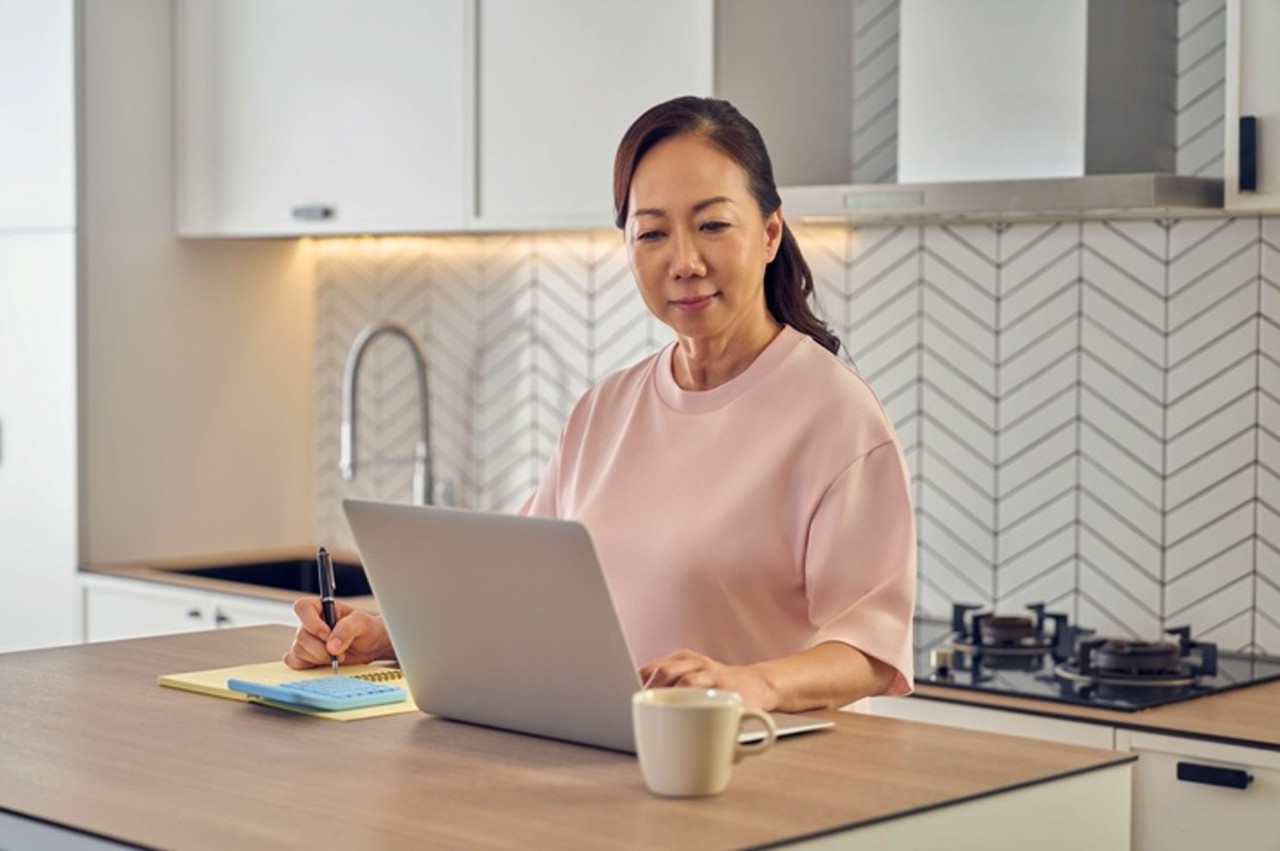Lady looking at her laptop in her kitchen