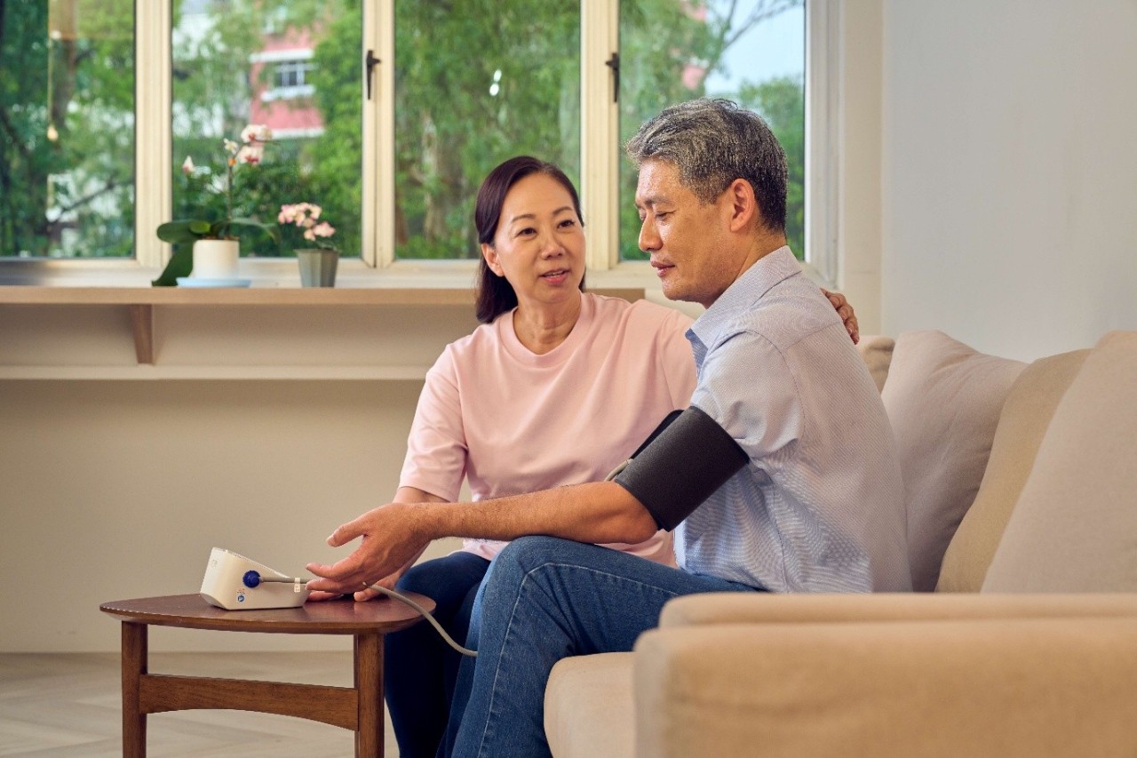 Lady helping her husband to take his blood pressure reading