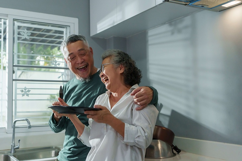 An elderly couple enjoying themselves in their kitchen