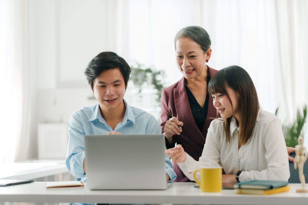 Group of adults discussing over a laptop